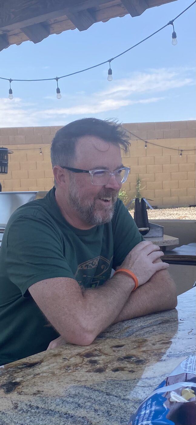 Chris laughing at an outdoor table